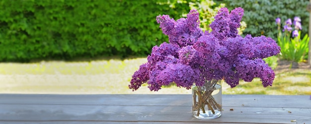 Lindo buquê de lilás roxo em uma mesa de madeira no jardim com vista panorâmica