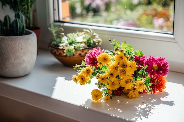 Lindo buquê de outono com flores amarelas de áster e crisântemo no parapeito da janela