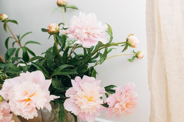 Lindo buquê de peônias no quarto boho moderno Flores de peônia rosa suave em vaso em fundo rústico imagem mal-humorada Decoração boêmia moderna, detalhes interiores elegantes e confortáveis