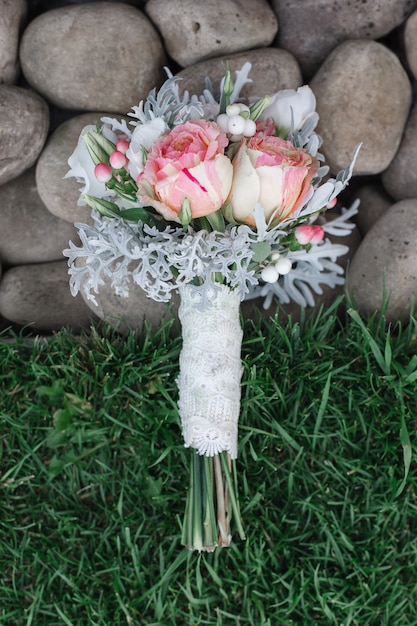 lindo buquê de rosas brancas e rosa na grama verde. arranjo de flores. Elegante bouquet de noiva ao ar livre com espaço. detalhes do casamento