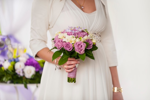 Lindo buquê de rosas roxas nas mãos da noiva em um casamento