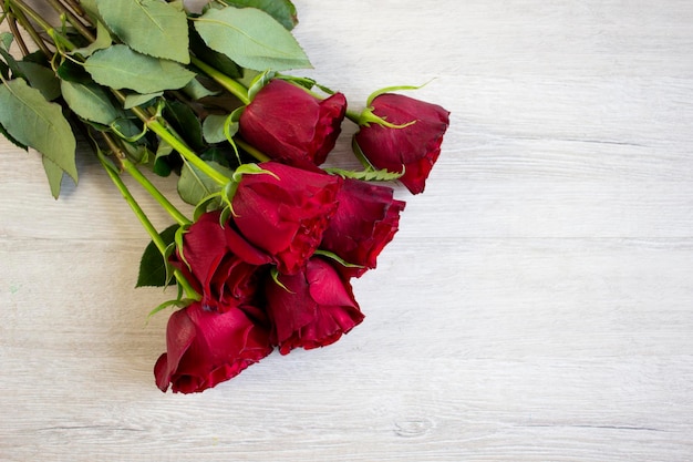 Lindo buquê de rosas vermelhas escuras sobre fundo de madeira claro fechado com espaço para cópia