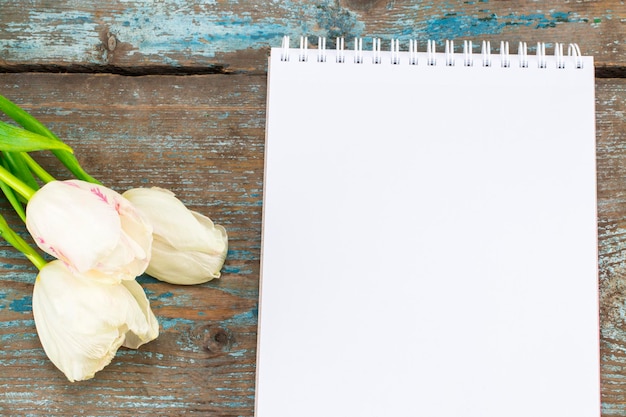 Lindo buquê de tulipas para o dia das mães e papel em branco com espaço vazio para um texto em fundo de madeira.