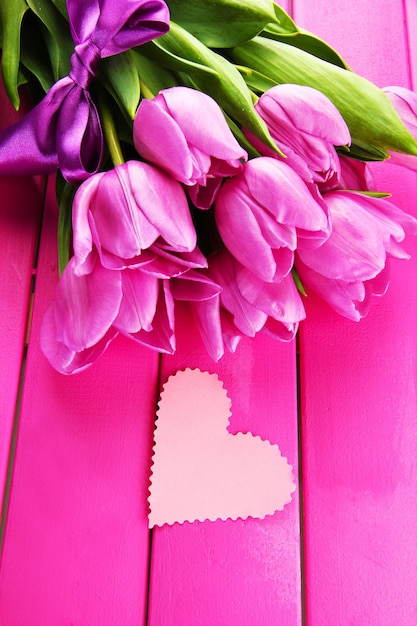 Lindo buquê de tulipas roxas em fundo rosa de madeira