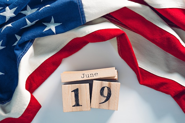 Foto lindo calendário de blocos de madeira com data 19 de junho e bandeira americana de algodão. conceito do décimo primeiro dia da independência nacional