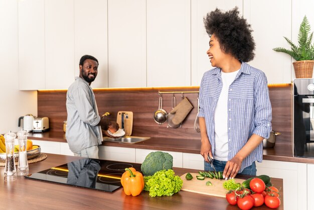 Lindo casal afro-americano cozinhando em casa - lindo e alegre casal negro preparando o jantar na cozinha