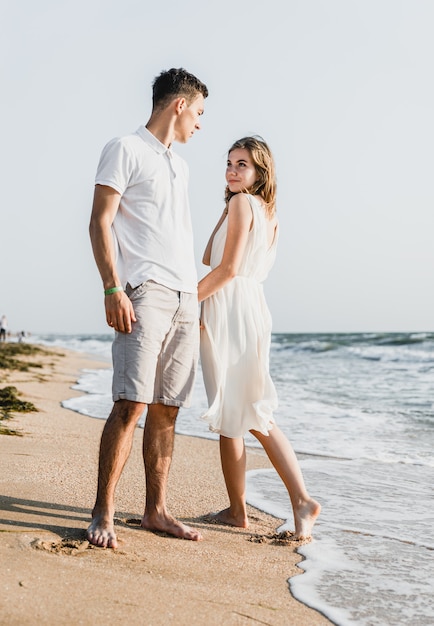 Lindo casal apaixonado caminha à beira-mar. casal jovem feliz passa um tempo na praia.