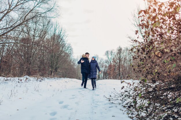 Lindo casal apaixonado caminhando juntos na floresta de inverno. Pessoas se divertindo ao ar livre