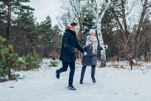 Lindo casal apaixonado correndo juntos na floresta de inverno. Pessoas se divertindo ao ar livre