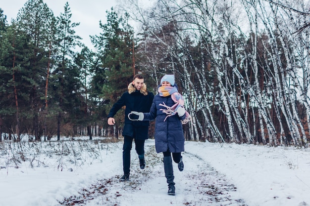 Lindo casal apaixonado correndo juntos na floresta de inverno. pessoas se divertindo ao ar livre