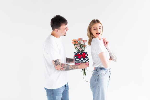 Lindo casal apaixonado em casa comemorando com uma caixa de presente e troca de flores