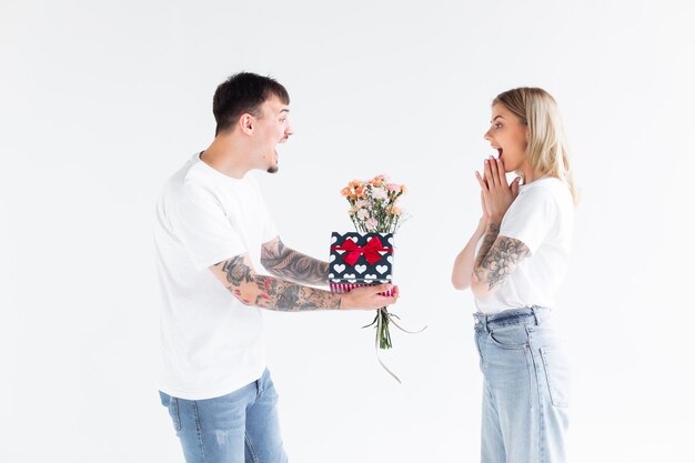 Lindo casal apaixonado em casa comemorando com uma caixa de presente e troca de flores