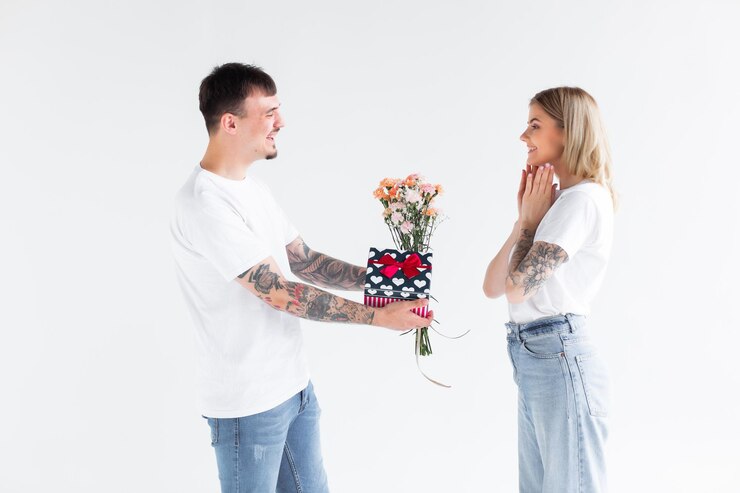 Lindo casal apaixonado em casa comemorando com uma caixa de presente e troca de flores