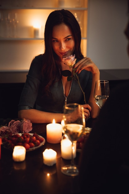 Foto lindo casal apaixonado jantando à luz de velas em casa, mulher cheirando uma flor