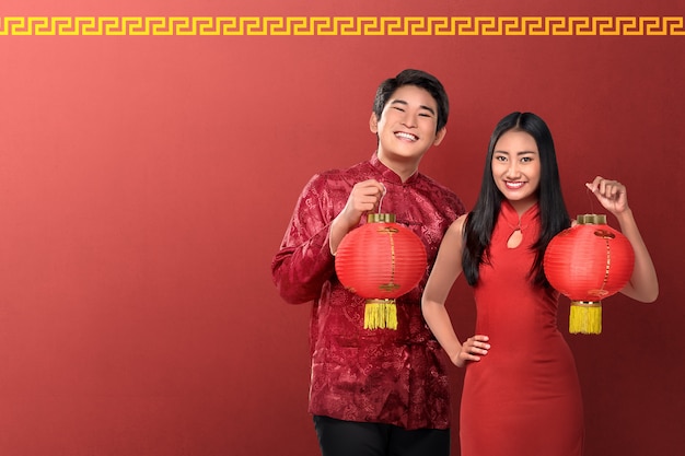 Lindo casal chinês segurando lanternas vermelhas em fundo vermelho