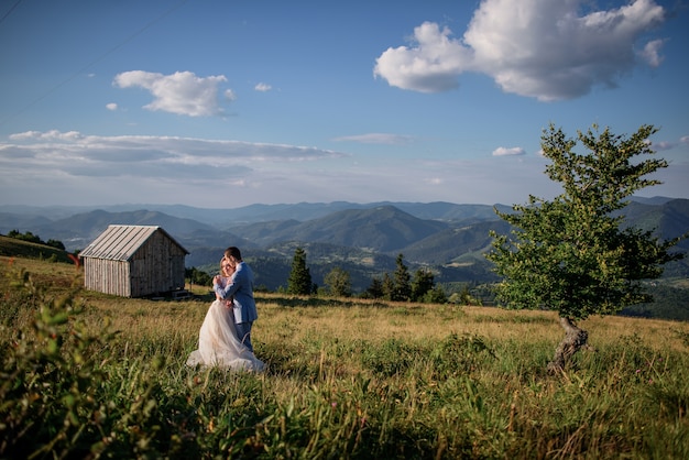 Lindo casal coloca entre árvores na colina com paisagem montanhosa por trás