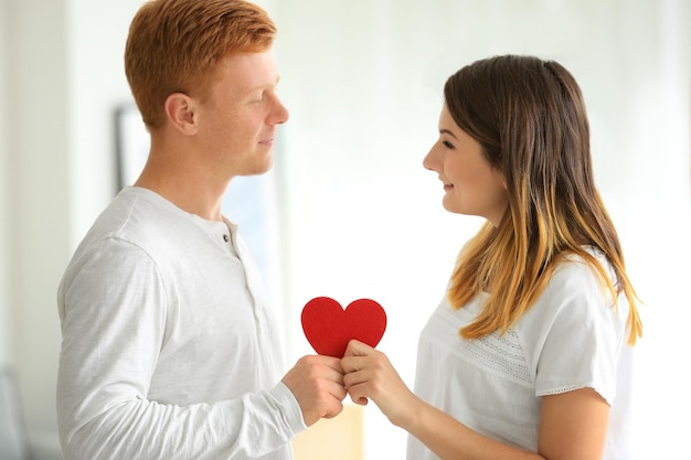 Lindo casal com coração vermelho na sala de luz