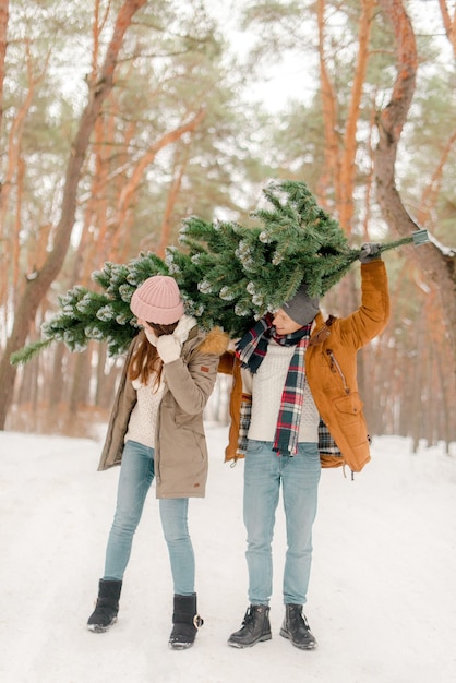 Lindo casal com uma árvore de Natal no bosque nevado