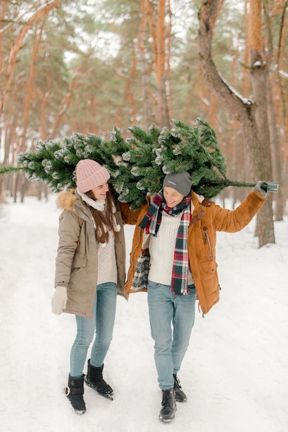 Lindo casal com uma árvore de Natal no bosque nevado