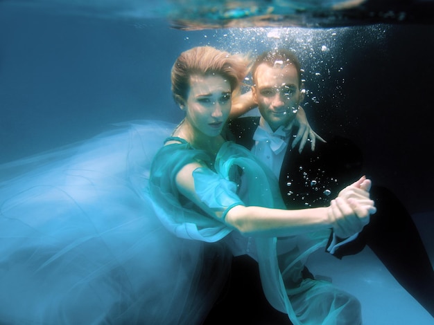 lindo casal dançando debaixo d'água na piscina