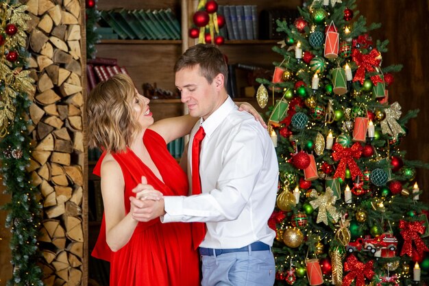 Lindo casal dançando na sala decorada pela árvore de natal comemorando a festa de ano novo