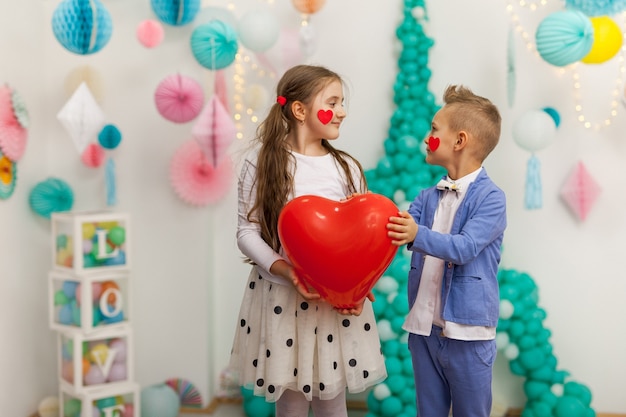 Lindo casal de crianças com balão de coração vermelho. Dia dos Namorados e conceito de amor, estúdio tiro