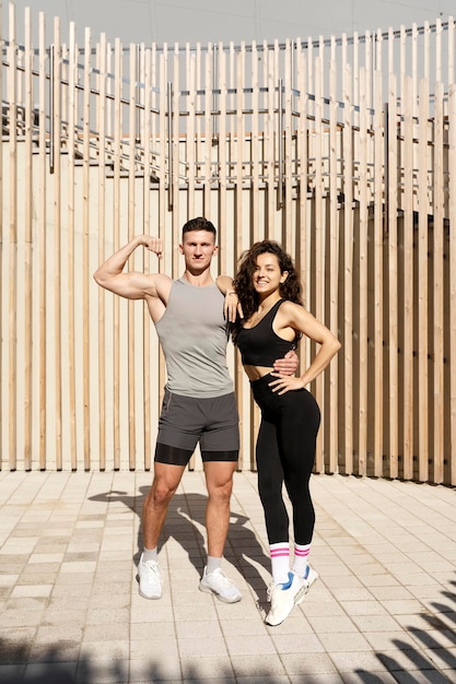 Lindo casal de fitness vestindo roupas esportivas elegantes está posando na rua da cidade