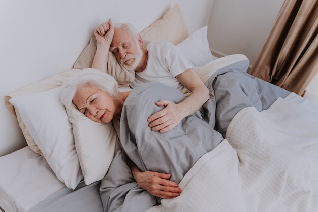Lindo casal de idosos curtindo o tempo juntos em casa - Idosos dormindo na cama em casa