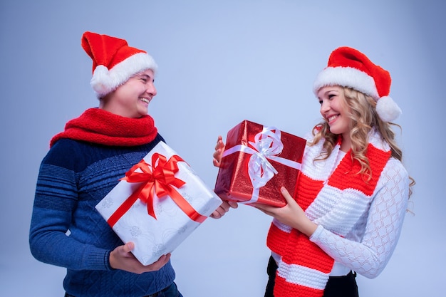 Lindo casal de Natal com chapéu de Papai Noel segurando presentes sobre fundo azul