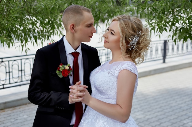 Lindo casal de noivos amorosos registra um casamento e caminha ao longo do belo calçadão. felicidade e amor aos olhos de homens e mulheres. rússia, sverdlovsk, 15 de junho de 2019