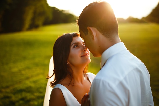 Lindo casal de noivos ao pôr do sol Noiva noivo em traje de casamento com buquê de flores Romântico