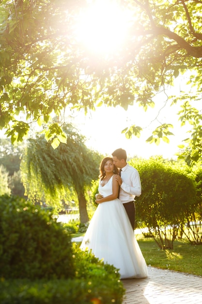 Lindo casal de noivos ao pôr do sol Noiva noivo em traje de casamento com buquê de flores Romântico