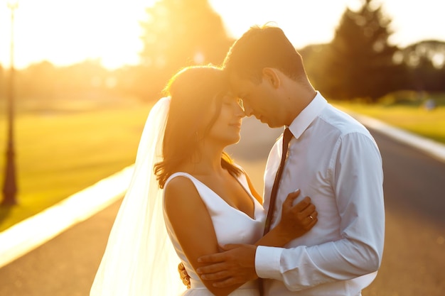 Lindo casal de noivos ao pôr do sol Noiva noivo em traje de casamento com buquê de flores Romântico