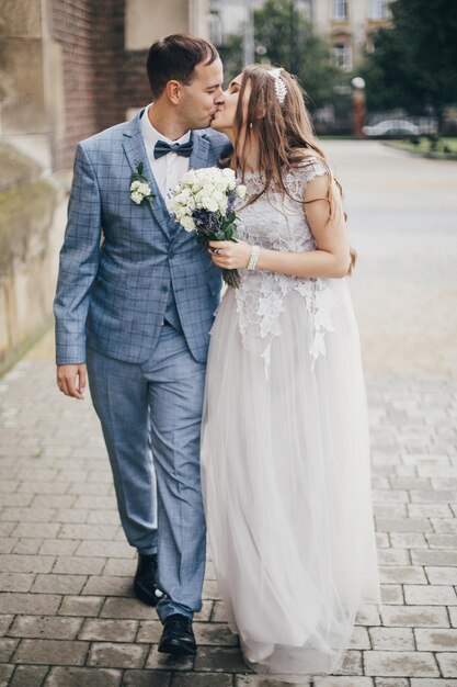Lindo casal de noivos emocionados beijando e caminhando no casamento da Provença na cidade europeia