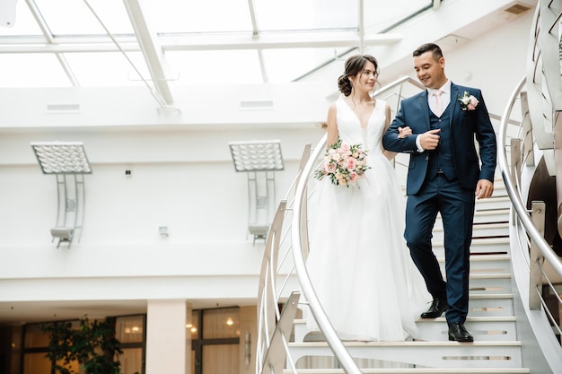 Lindo casal de noivos sobe as escadas e sorri