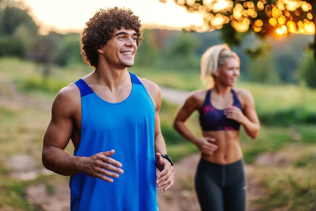 Foto lindo casal desportivo correndo na natureza, no dia de verão ensolarado.