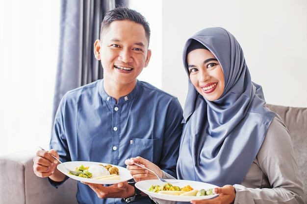 lindo casal do sudeste asiático comendo uma refeição festiva na celebração do eid