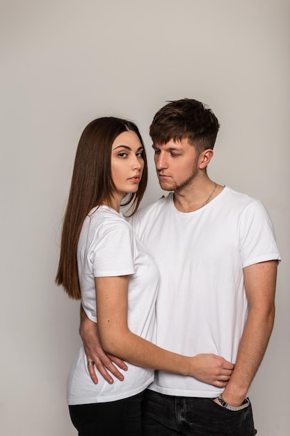 Lindo casal elegante apaixonado por uma camiseta branca de moda com um espaço de cópia para design no estúdio. cara bonito na moda com penteado e garota bonita sexy