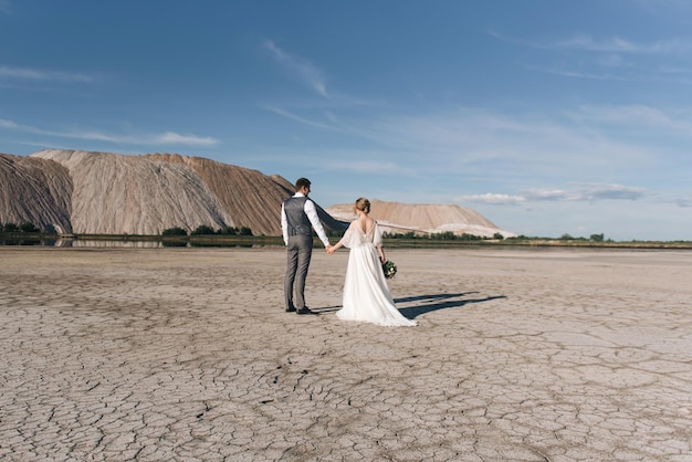 Lindo casal elegante de recém-casados apaixonados em um belo fundo natural de montanhas de sal e pedreiras