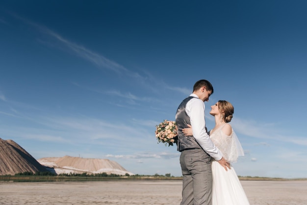 Lindo casal elegante de recém-casados apaixonados em um belo fundo natural de montanhas de sal e pedreiras