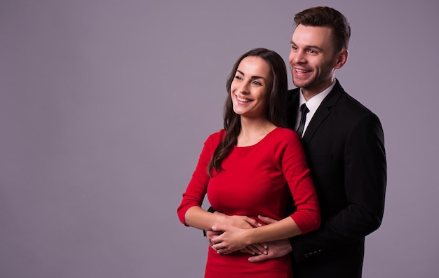 Lindo casal elegante e elegante de terno e vestido estão se abraçando, divirta-se e posando isolado no estúdio. Feriados e eventos. Dia de São Valentim. Dia dos namorados