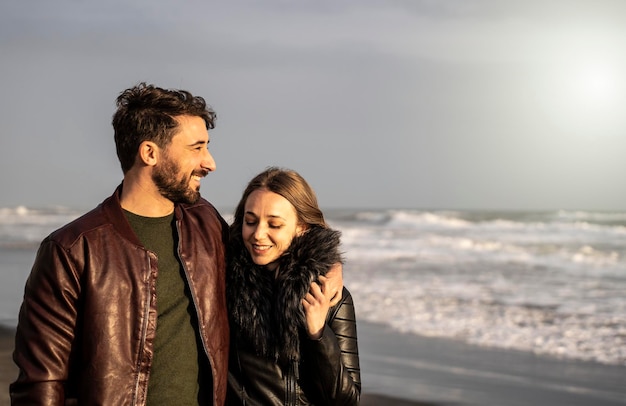 Lindo casal em relacionamento abraçando e amando um ao outro no primeiro namoro Menina e menino curtindo a atividade de lazer ao ar livre na praia romântica na temporada de outono Relacionamento de casal