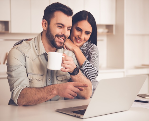 Lindo casal está usando um laptop e tomando café