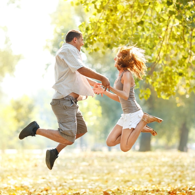 Lindo casal feliz tocando no parque e de mãos dadas