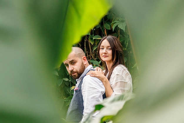 Lindo casal garota e cara no parque entre árvores tropicais