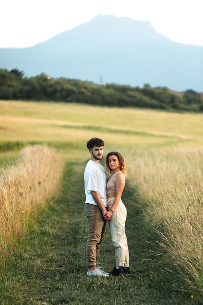 Lindo casal heterossexual em um campo de grama caminhando e se beijando