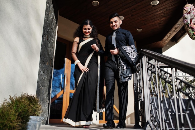 Lindo casal indiano apaixonado usa no saree e terno elegante posou no terraço ao ar livre no dia ensolarado de verão andando no andar de baixo e de mãos dadas