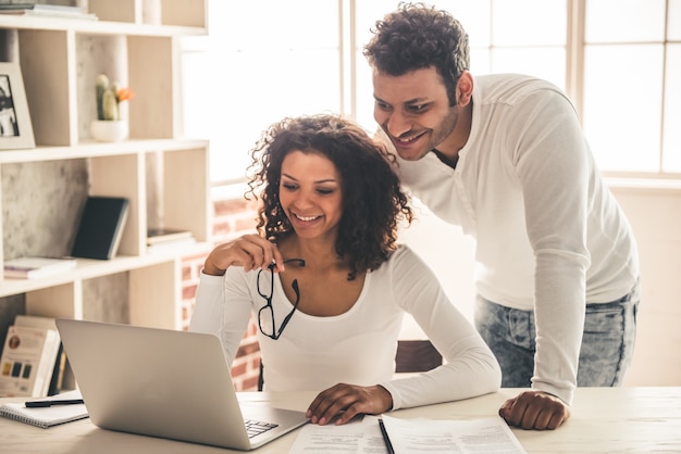 Lindo casal jovem afro-americano está usando um laptop