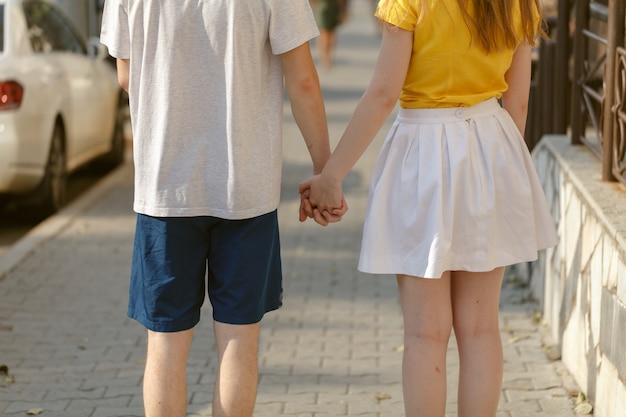 Lindo casal jovem anda de mãos dadas na estrada