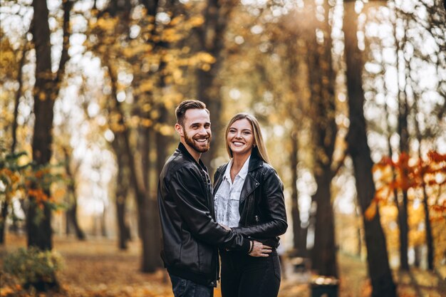 Lindo casal jovem andando no parque outono em um dia ensolarado